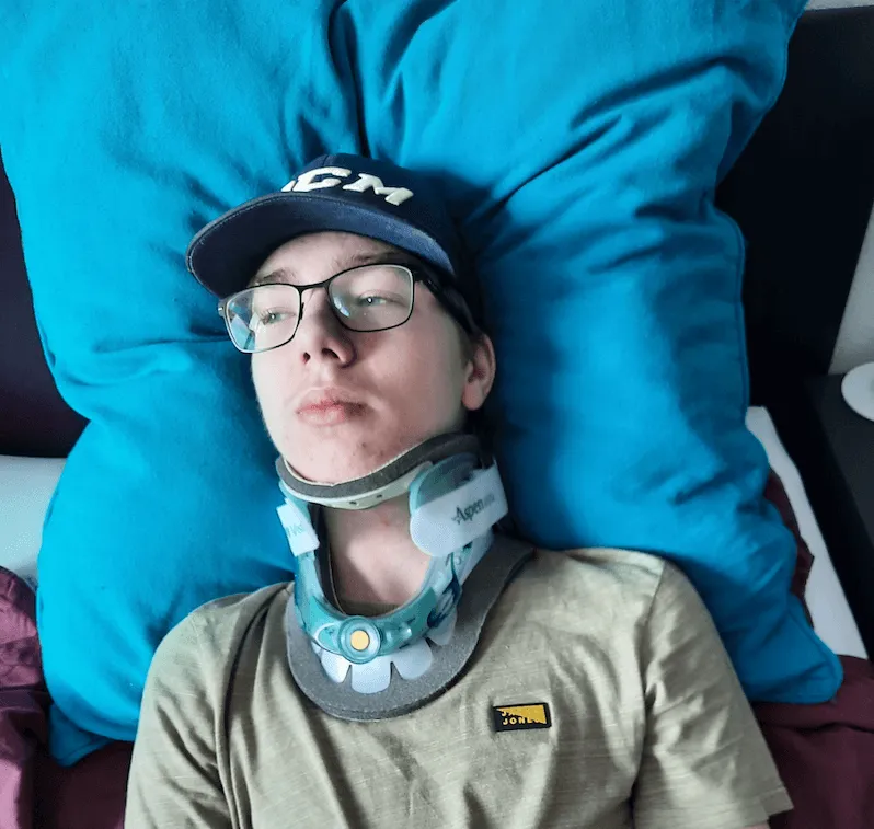 Niek ligt met nekkraag en pet op een blauw kussen