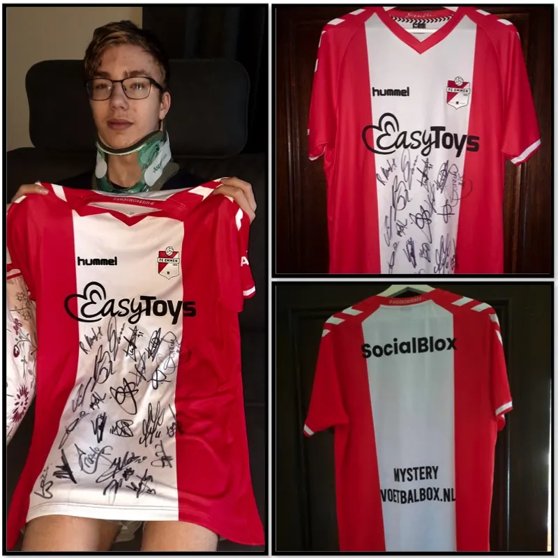 Niek met nekkraag houdt een rood-wit, gesigneerd shirt van FC Emmen omhoog
