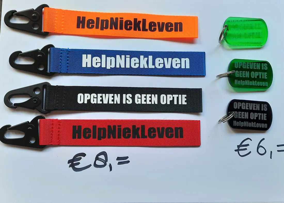 Vier keycords in oranje, blauw, zwart en rood met de teksten HelpNiekLeven en Opgeven is geen optie, met groene en zwarte dog tags