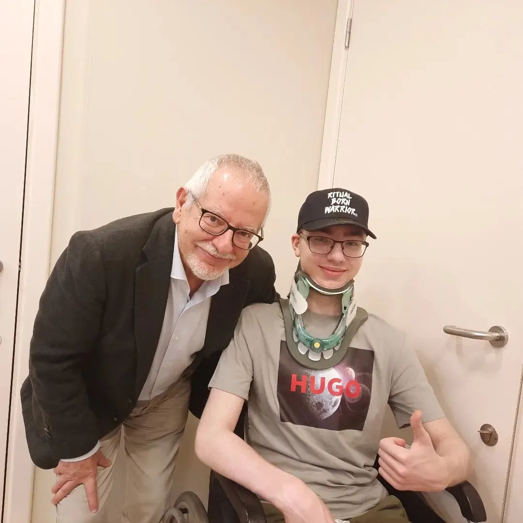 Niek met nekkraag steekt zijn duim op naast een arts in een donker colbert