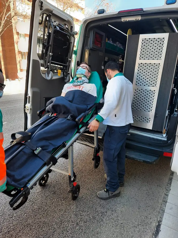 Niek wordt op een brancard uit een ziekenwagen gereden